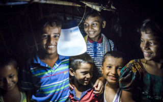 Rohingya boys hold a solar lamp that is sustainable