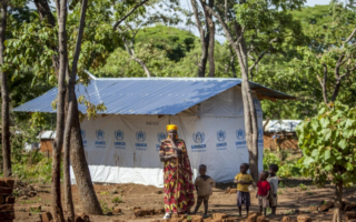 A woman and her family stand outside their house in Burundi