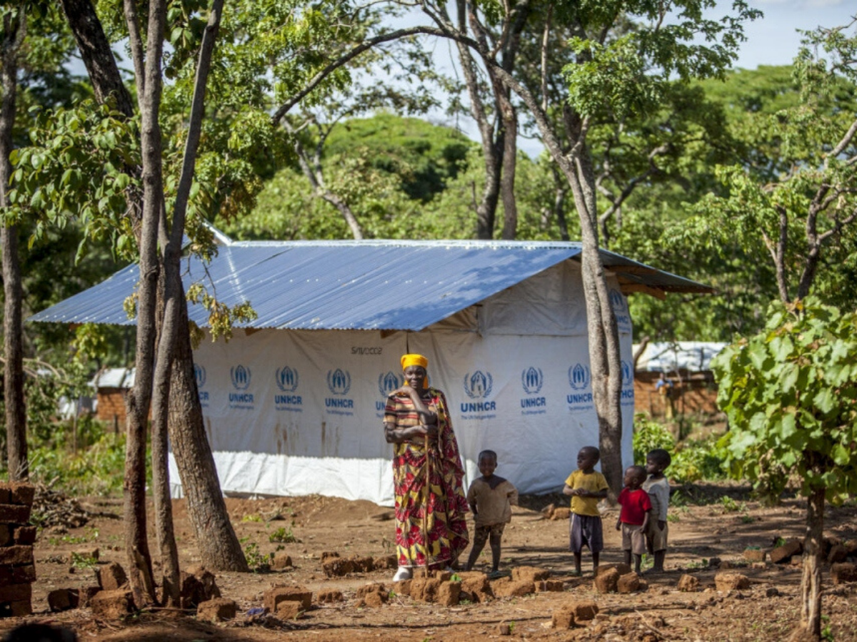 A woman and her family stand outside their house in Burundi