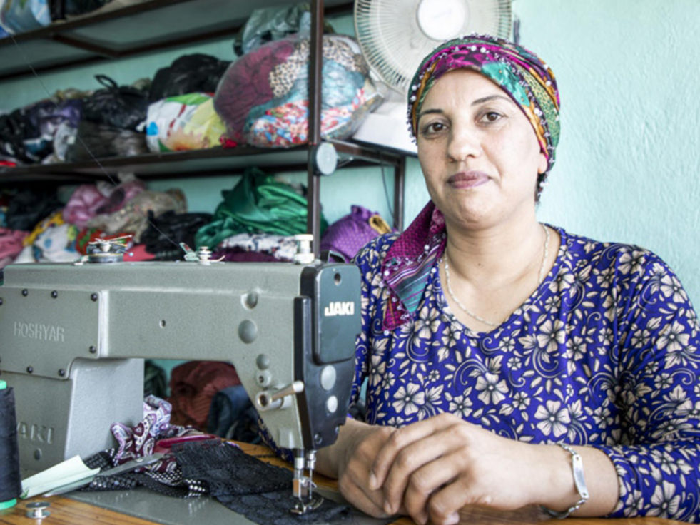 A seamstress from Syria sits at a sewing machine