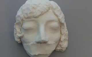 sculpture of an unknown woman's face with her mouth taped shut to commemorate plight of people who are stateless