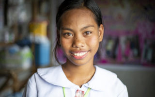 A girl who experienced statelessness smiles at the camera