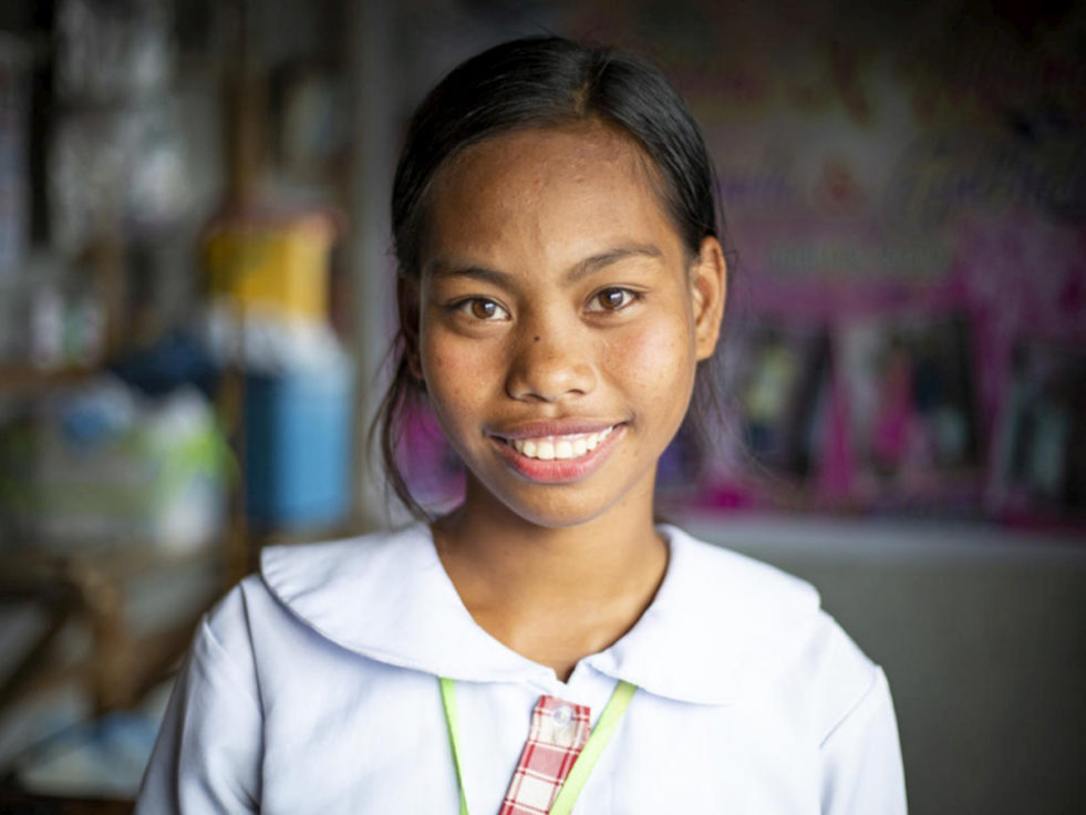 A girl who experienced statelessness smiles at the camera