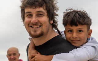 A man gives a piggyback to a boy from Syria