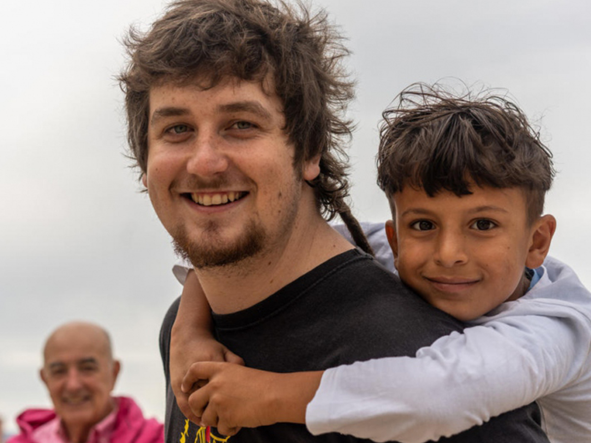 A man gives a piggyback to a boy from Syria
