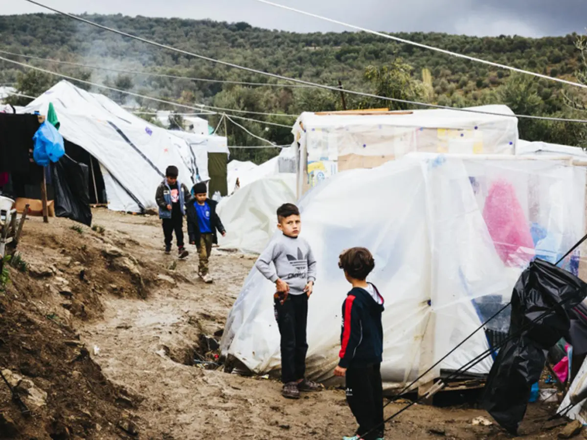 Boys stand outside tents on a Greek island