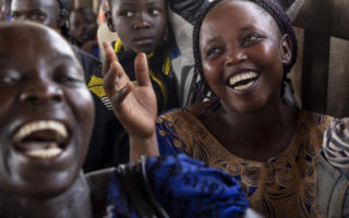 Débordante de joie, Guilaine Alaya (à droite) chante à tue-tête à bord du bateau qui la ramène à Bangui, capitale de la République centrafricaine, après six ans en exil