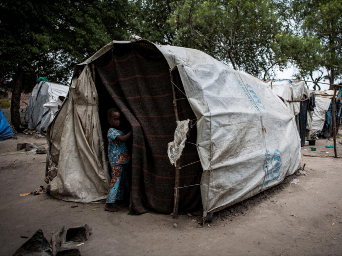 A child from the DRC stands outside a tent