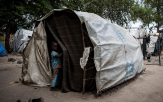 Un enfant se tient à l’entrée d’une tente dans un site de déplacés internes à Kasenyi
