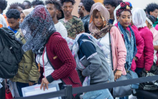 Refugees stand outside an airport