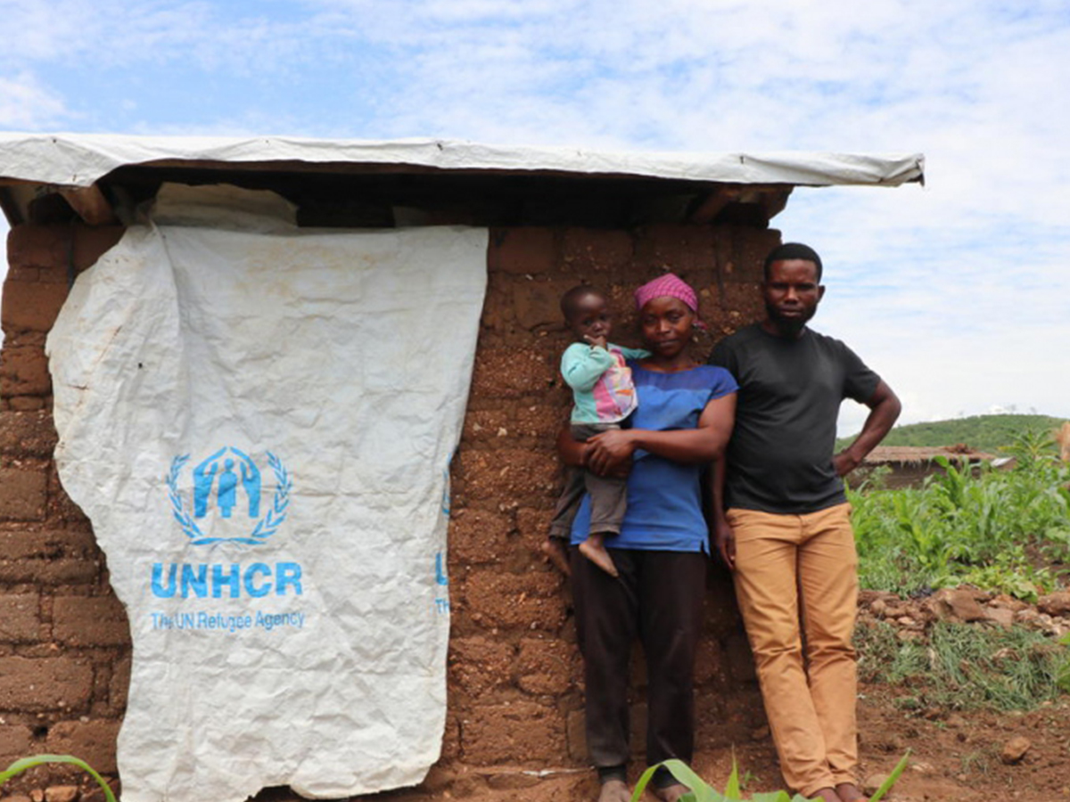 Les réfugiés burundais, Aïcha, son mari Matias et leur enfant se tiennent à côté des toilettes qu'ils ont construites dans le camp de Mulongwe, en République démocratique du Congo
