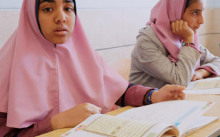 Two Afghan students sit at their desks