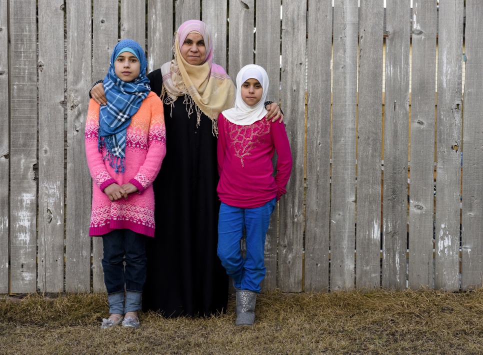 A Syrian mother stands outside with her two daughters