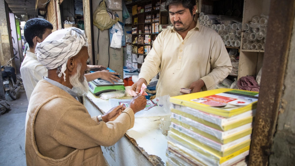 Azeem, 27 ans, dans son magasin à Karachi, au Pakistan. Les réfugiés afghans comme Azeem ont récemment été autorisés à ouvrir des comptes bancaires