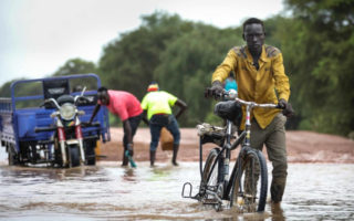 A man rides a bike through water in South Sudan