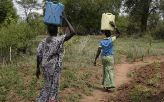 Two people carry water in Uganda