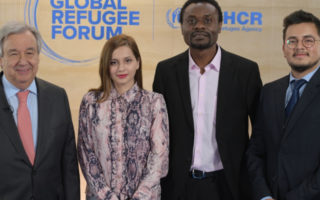 Three men and one woman standing at Global Refugee Forum