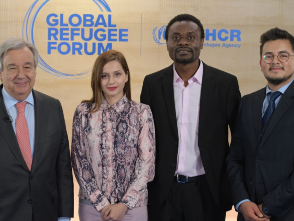 Three men and one woman standing at Global Refugee Forum