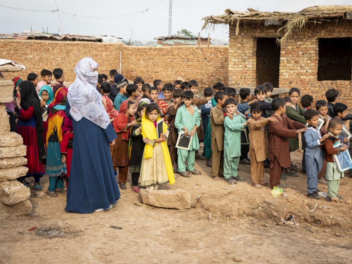 Afghan refugee children stand outside a school