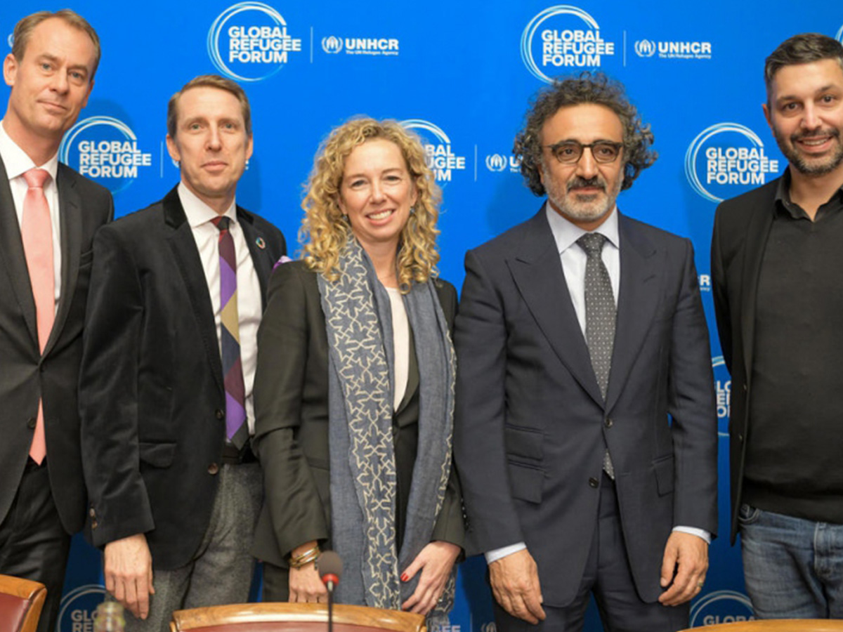 A group of people smile at the camera at the Global Refugee Forum