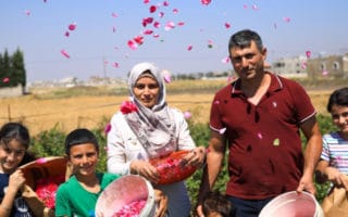famille de réfugiés syriens devant une ferme rose