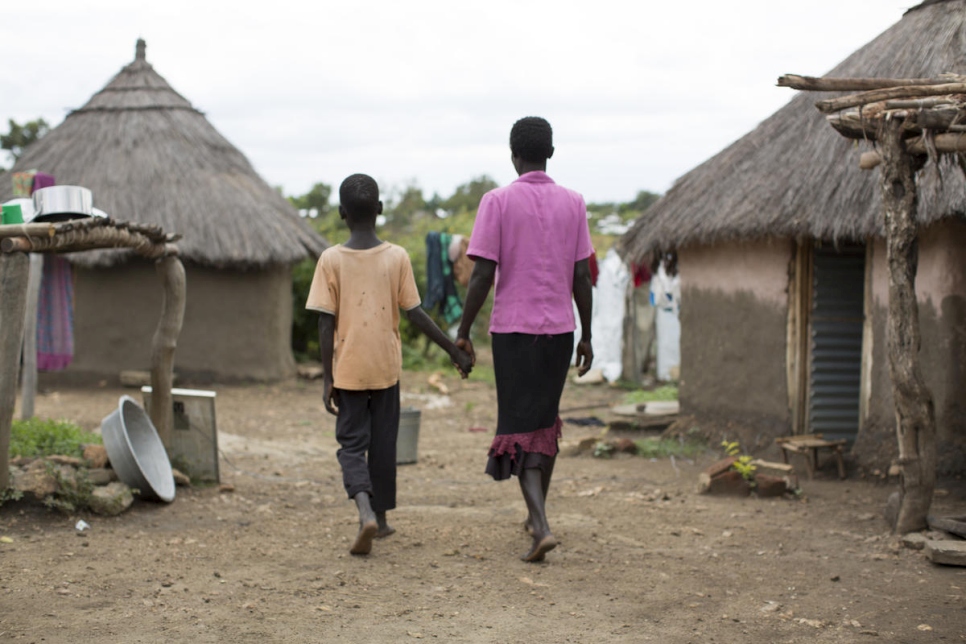 Refugees from South Sudan walk hand in hand through a settlement in Uganda