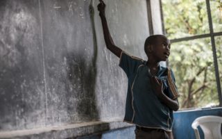 Boy points to something on a chalkboard in Ethiopia