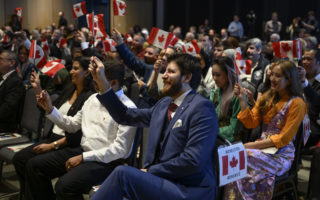 Tareq Hadhad, réfugié syrien et fondateur de Peace by Chocolate, se joint à 48 autres nouveaux Canadiens pour brandir leurs drapeaux canadiens à la suite d'une cérémonie de citoyenneté canadienne au Quai 21 à Halifax, en Nouvelle-Écosse, le mercredi 15 janvier 2020