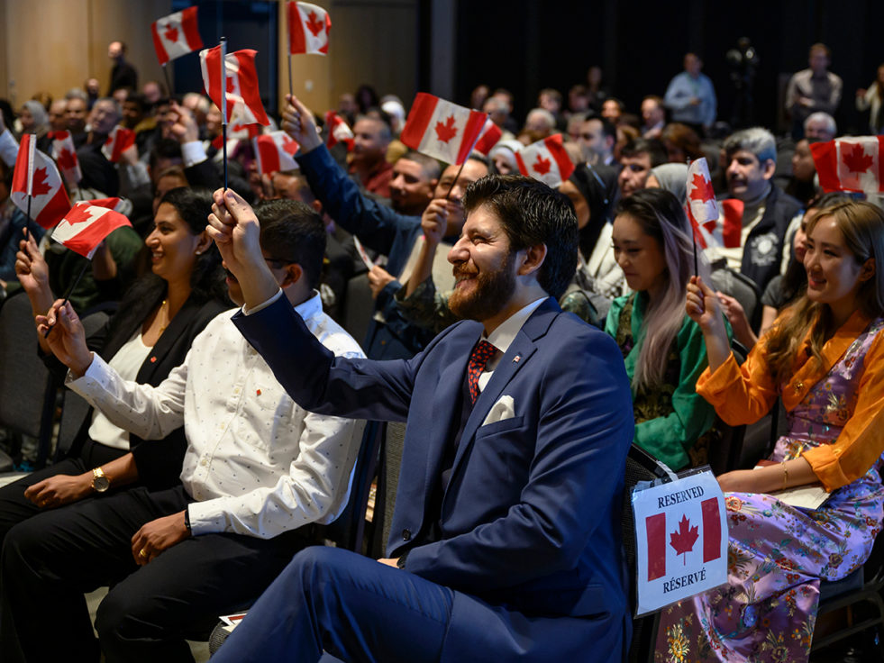 Tareq Hadhad, a Syrian refugee and founder of Peace by Chocolate, joins 48 other new Canadians in waving their Canadian flags following a Canadian citizenship ceremony at Pier 21 in Halifax, Nova Scotia on Wednesday, January 15, 2020.