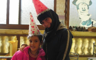 Two young girls smile for the camera at the SOS Children’s Villages in Syria, where Abrar worked
