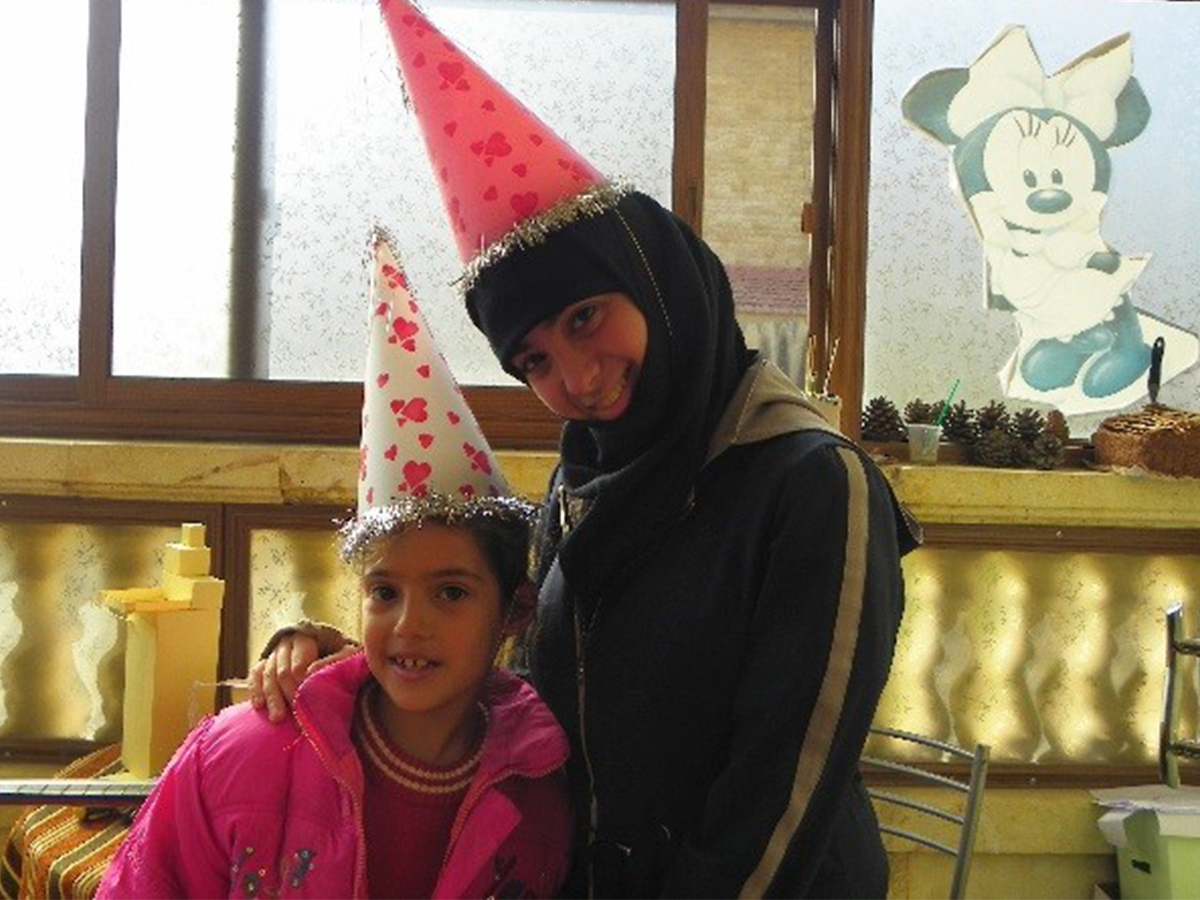 Abrar Mechmechia smiles with a young girl whom she worked with at the SOS Children's Villages in Syria. 