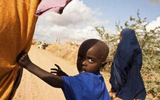 child refugee holding hands with mother