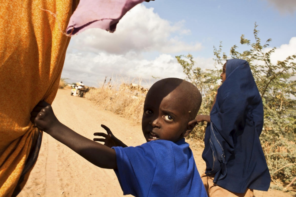 child refugee holding hands with mother