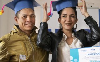 Two refugees hold graduation cap in Ecuador