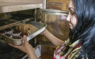 Refugee puts baked goods in the oven