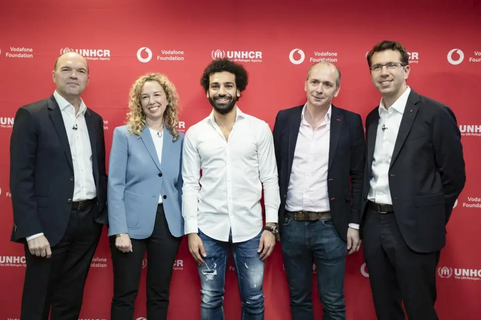 A group of professionals a stand in front of a red step and repeat backdrop