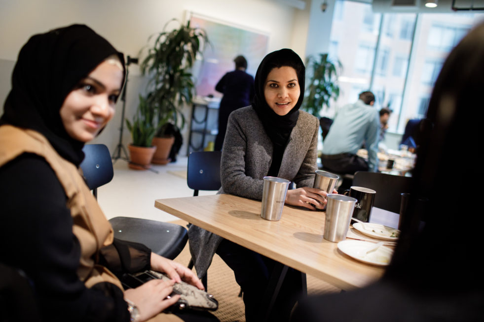 A group of refugee women in Canada sit around a table talking