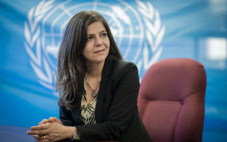 UNHCR Representative in Canada, Rema Jamous, poses in front of a UN flag