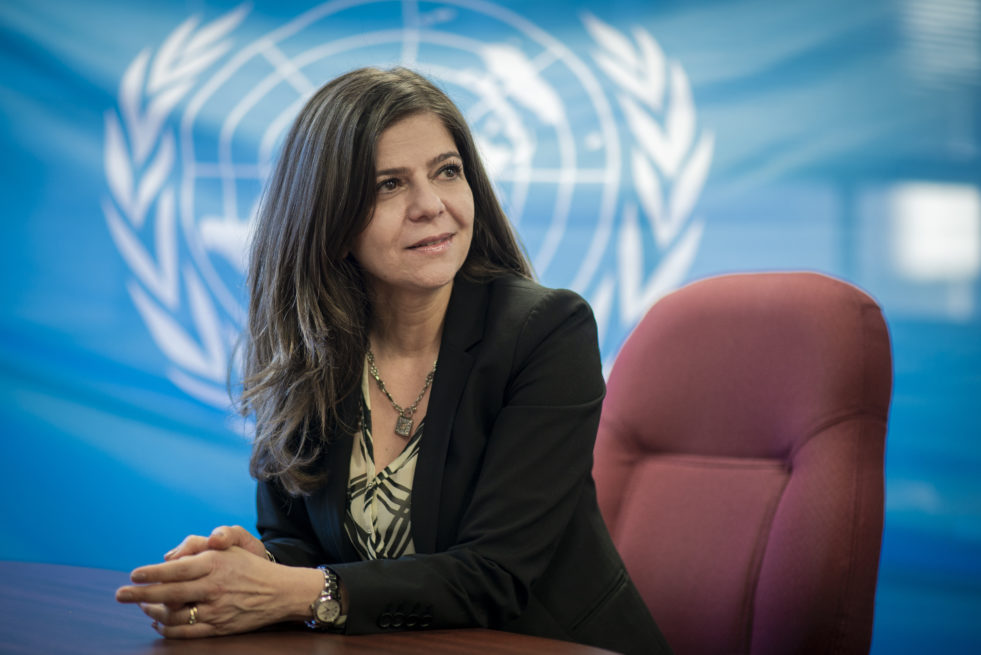 UNHCR Representative in Canada, Rema Jamous, poses in front of a UN flag