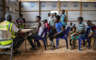 Cameroon refugees sit in line for registration