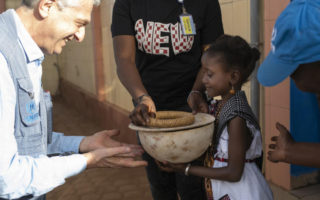 High Commissioner receives a bowl from a young girl in Burkina Faso
