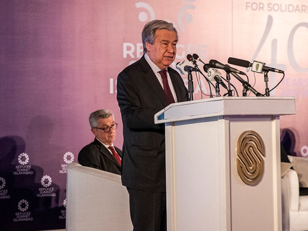 UN Secretary general stands on a podium speaking into several mics