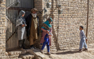 People standing outside of a building in Pakistan looking at a little boy