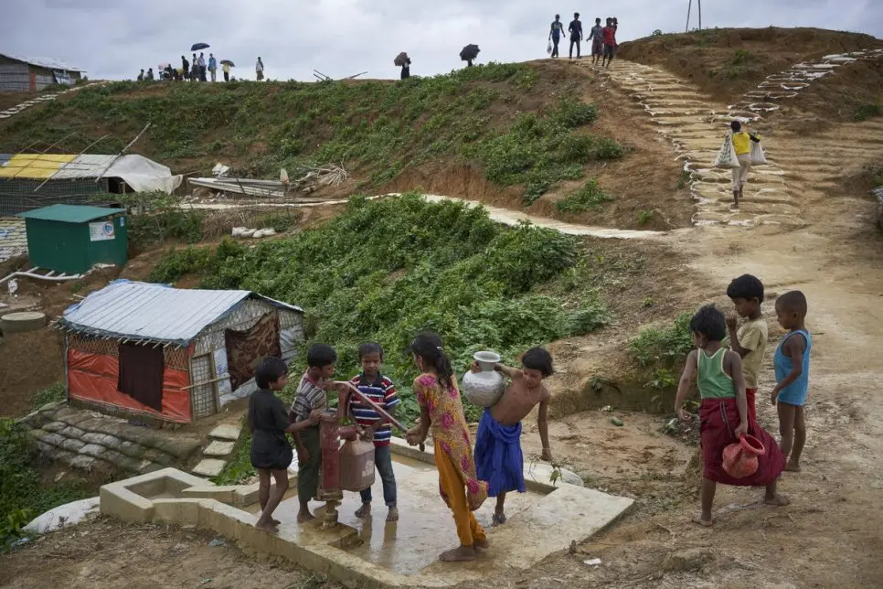 Rohingya children stand in line for a water pump