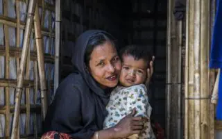 A Rohingya woman hugs a baby