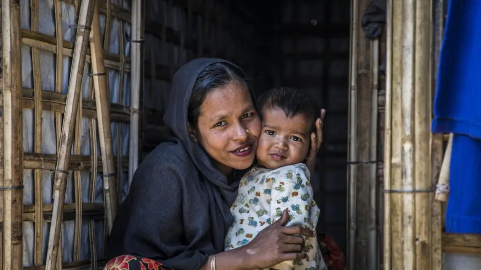 A Rohingya woman hugs a baby