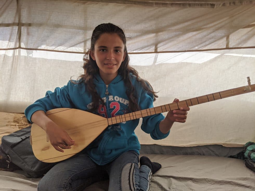 Young girl from Syria playing a stringed instrument called a tanbur