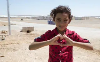 Portrait of a young girl making a love heart with her hands