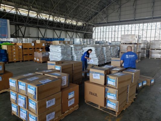People working in a supply house wearing WHO and WFP branded visibility clothing