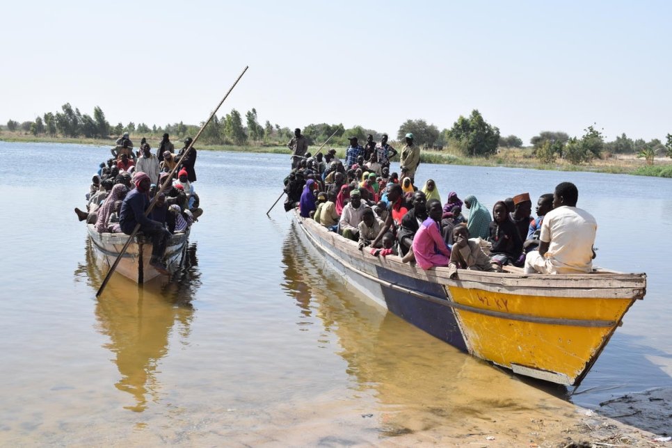 Two boats full of people on the bank of a river